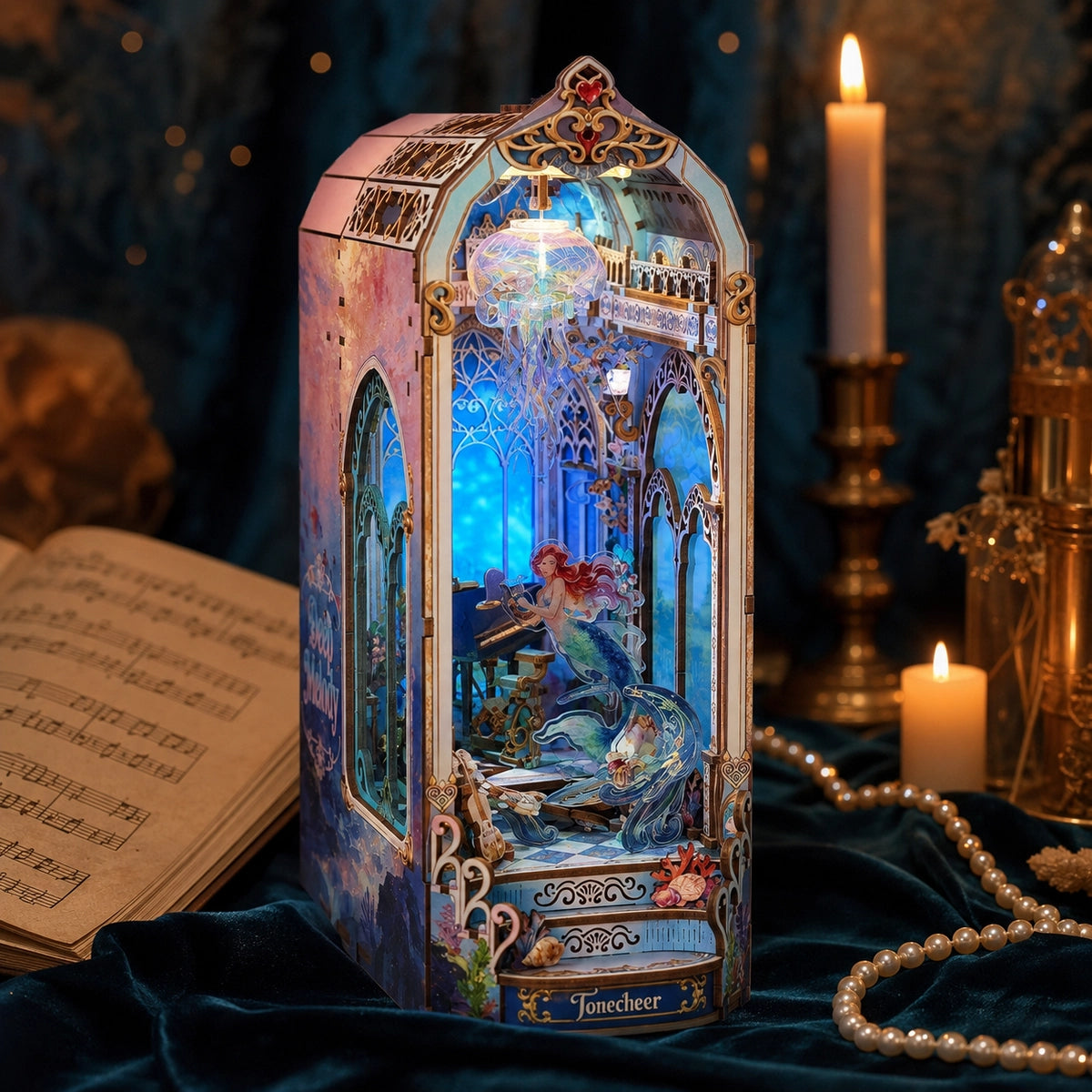 Book nook Deep Melody come decorazione d’atmosfera accanto a libri e candele