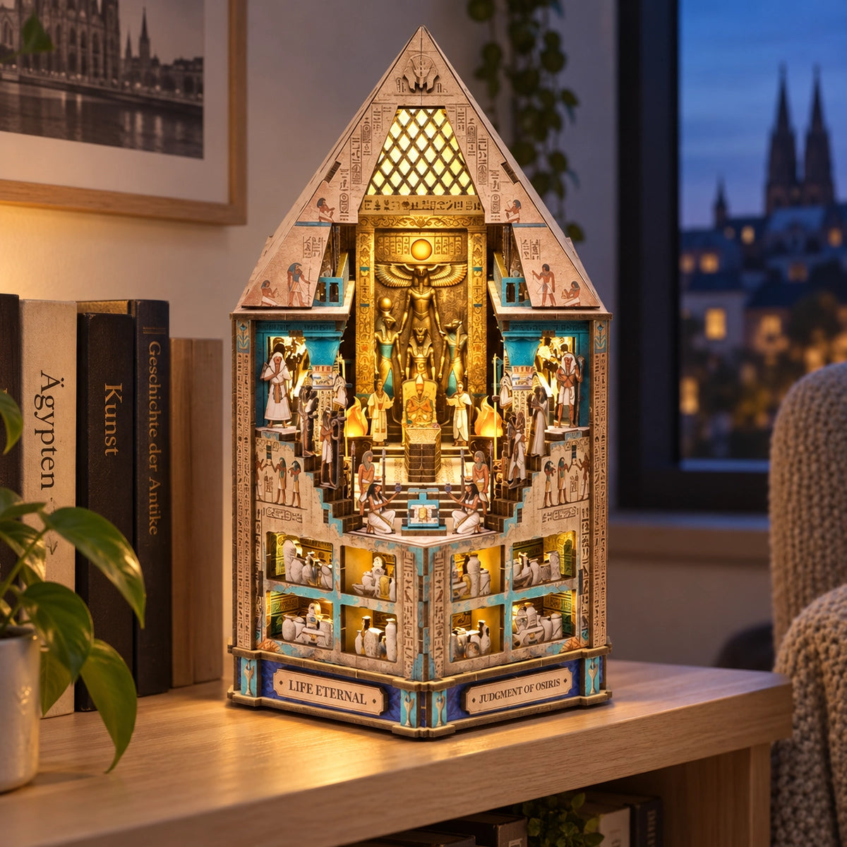 Oświetlona egipska miniatura Hall of Eternity z piramidalnym szczytem obok książek