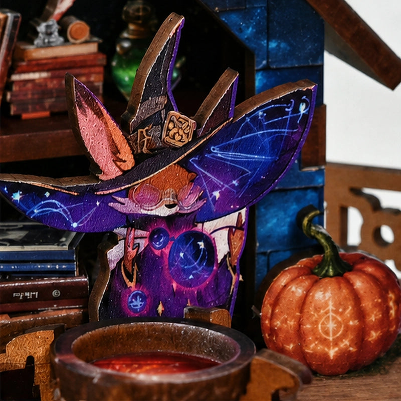 Kleine violette Figur mit Sternenhut neben Kessel und verziertem Kürbis