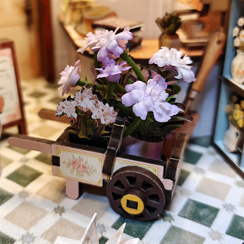 Kleiner Blumenwagen mit violetten, weißen und rosa Blüten