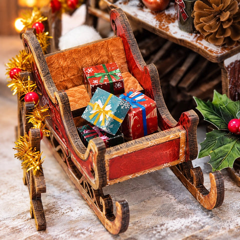 Roter Miniaturschlitten mit bunten Geschenkpaketen